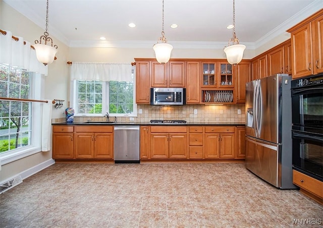 4786 Ormonde Dr, Cazenovia, NY 13035 - kitchen featuring appliances with stainless steel finishes, brown cabinetry, a sink, dark countertops, and crown molding