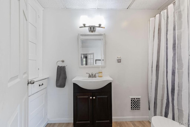 173 Mosley Dr Unit 1, Syracuse, NY 13206 - bathroom featuring a paneled ceiling, vanity, wood finished floors, toilet, and baseboards