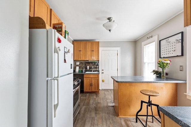 173 Mosley Dr Unit 1, Syracuse, NY 13206 - kitchen with freestanding refrigerator, dark wood-type flooring, stainless steel range, a peninsula, and decorative backsplash