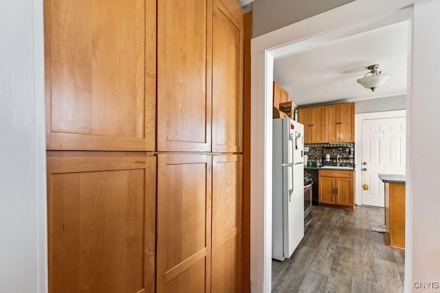 173 Mosley Dr Unit 1, Syracuse, NY 13206 - kitchen featuring freestanding refrigerator, tasteful backsplash, dark wood finished floors, brown cabinetry, and a sink