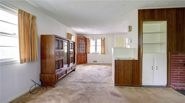 914 Waterloo Geneva Rd, Waterloo, NY 13165 - unfurnished living room featuring light carpet, a chandelier, a textured ceiling, and baseboards