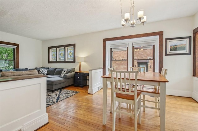 865 Harvard St, Rochester, NY 14610 - dining room featuring light wood-style flooring, a chandelier, a textured ceiling, and baseboards