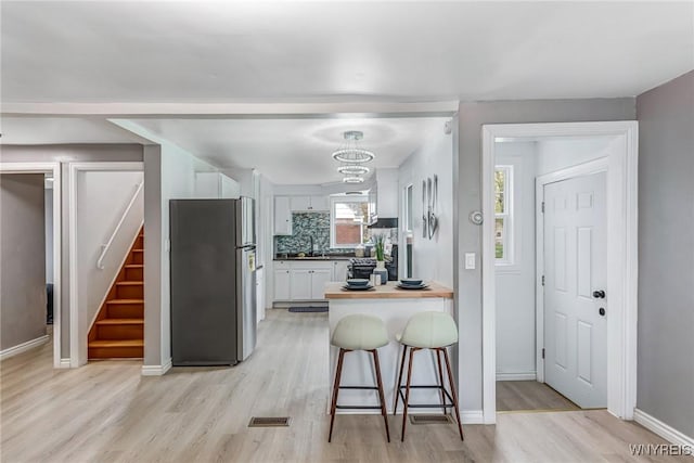 296 Burke Dr, Cheektowaga, NY 14215 - kitchen featuring freestanding refrigerator, white cabinetry, light wood finished floors, and a peninsula