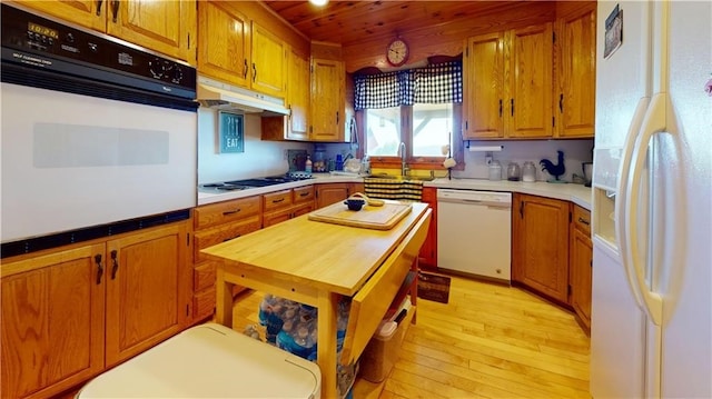 120 Fisher Ln, Afton, NY 13730 - kitchen with white appliances, under cabinet range hood, brown cabinetry, light wood-style floors, and light countertops