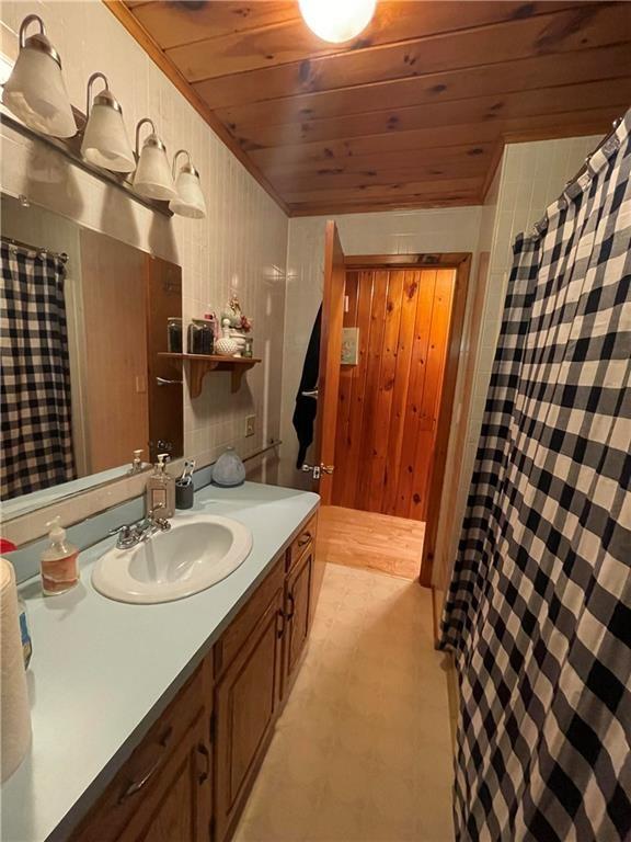 120 Fisher Ln, Afton, NY 13730 - bathroom featuring tile patterned floors, wood ceiling, vanity, wood walls, and a shower with curtain
