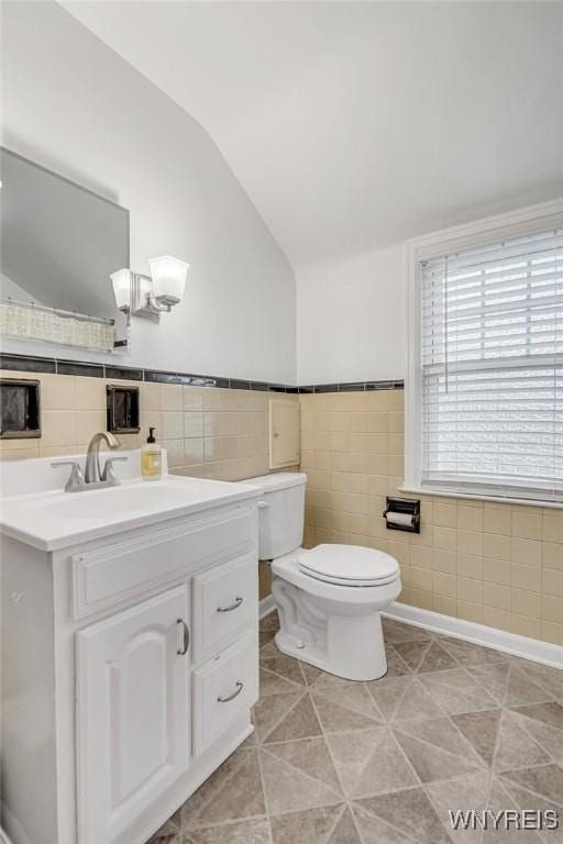 370 Mount Vernon Rd, Amherst, NY 14226 - half bath with tile walls, vaulted ceiling, toilet, vanity, and tile patterned flooring