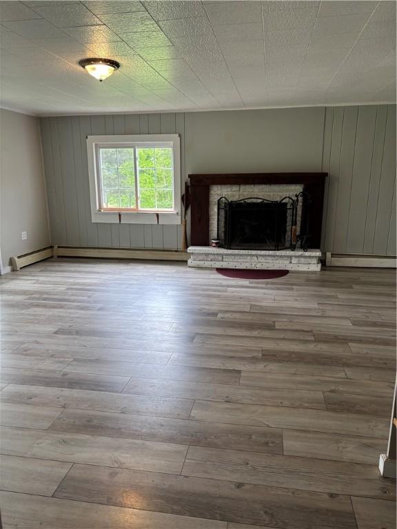 115 Depew Rd, Tioga, NY 13734 - unfurnished living room featuring wood finished floors, baseboard heating, a fireplace, and wooden walls