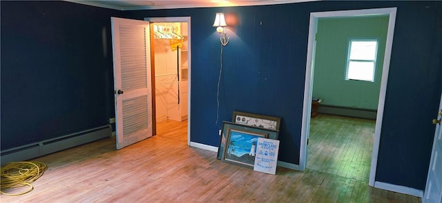 12034 Washington St, Wolcott, NY 14590 - empty room featuring a baseboard heating unit, wood finished floors, crown molding, and baseboards