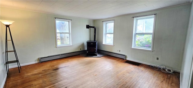 12034 Washington St, Wolcott, NY 14590 - unfurnished room with a wood stove, hardwood / wood-style flooring, a baseboard heating unit, healthy amount of natural light, and crown molding