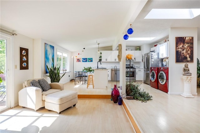 2804 Westinghouse Rd, Horseheads, NY 14845 - living area with washer and clothes dryer, healthy amount of natural light, a skylight, light wood-type flooring, and vaulted ceiling