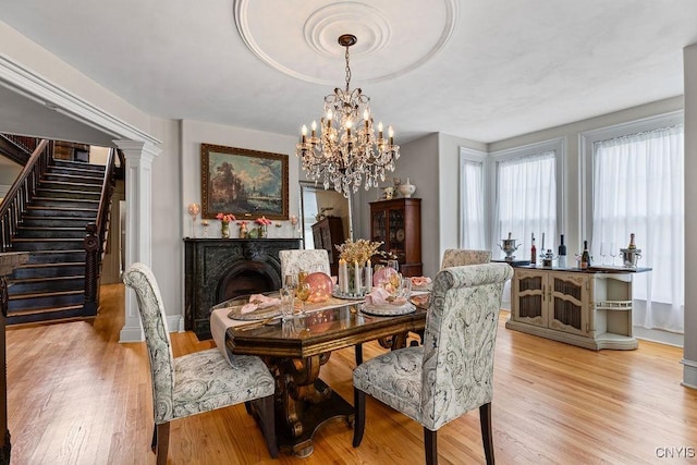 54 W 5th St, Oswego-City, NY 13126 - dining space featuring light wood-style floors, a chandelier, stairway, and baseboards