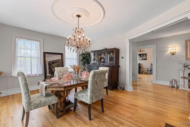 54 W 5th St, Oswego-City, NY 13126 - dining room featuring light wood-style floors, a chandelier, baseboards, and decorative columns