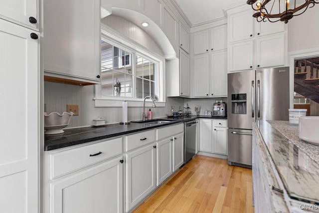 54 W 5th St, Oswego-City, NY 13126 - kitchen with stainless steel appliances, a sink, a chandelier, white cabinets, and light wood-style floors