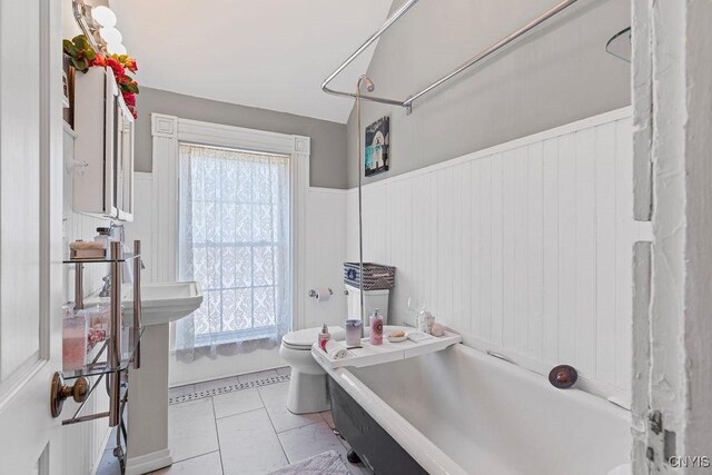 54 W 5th St, Oswego-City, NY 13126 - bathroom featuring a bath, toilet, tile patterned flooring, and a wainscoted wall