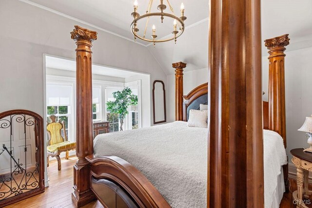 54 W 5th St, Oswego-City, NY 13126 - bedroom featuring a chandelier, wood-type flooring, ornamental molding, vaulted ceiling, and ornate columns