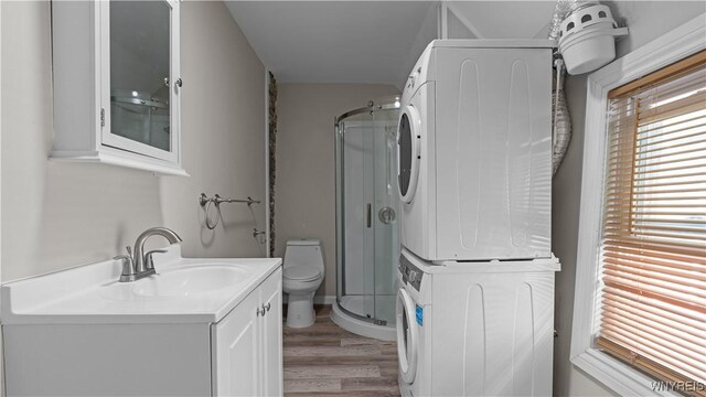 318 14th St, Buffalo, NY 14213 - full bath with estacked washer and dryer, toilet, a shower stall, vanity, and wood finished floors