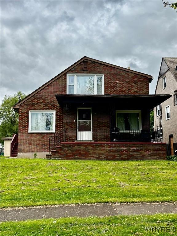761 4th St, Niagara Falls, NY 14301 - view of front of home featuring covered porch, brick siding, and a front lawn