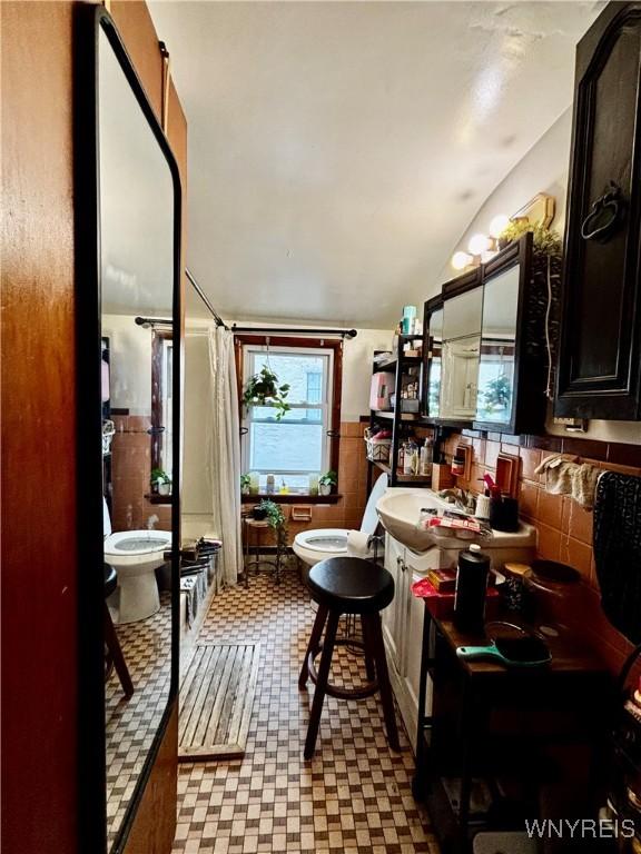 761 4th St, Niagara Falls, NY 14301 - full bathroom featuring tile patterned floors, vaulted ceiling, curtained shower, toilet, and a bath