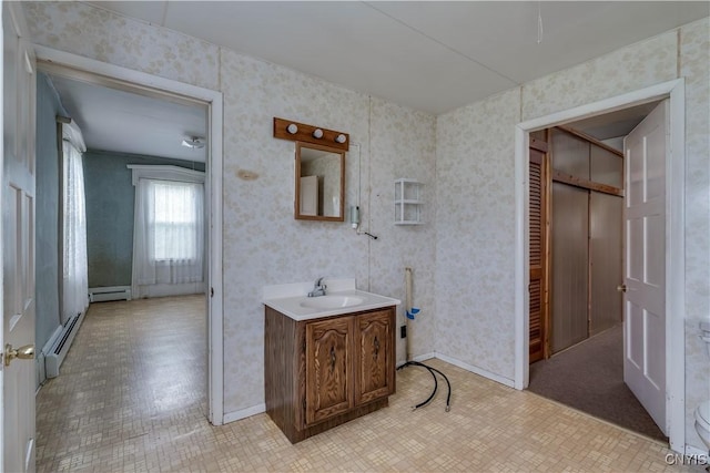 7709 Ridge Rd, Lowville, NY 13367 - bathroom with vanity, a baseboard heating unit, wallpapered walls, and baseboards