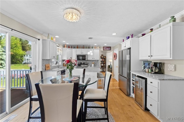 1660 Shallow Creek Trl, Webster, NY 14580 - dining room with wine cooler, light wood-style flooring, a chandelier, a bar, and recessed lighting