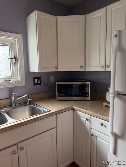 244 Parkwood Ave, Tonawanda-Town, NY 14217 - kitchen with freestanding refrigerator, stainless steel microwave, a sink, white cabinetry, and light countertops