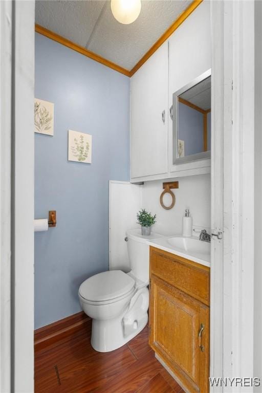 2654 Main St, Newfane, NY 14108 - half bath with crown molding, vanity, toilet, wood finished floors, and baseboards