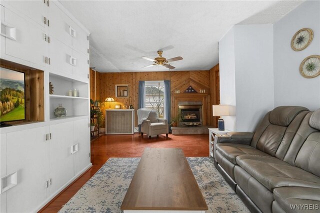 2654 Main St, Newfane, NY 14108 - living area featuring a ceiling fan, wooden walls, dark wood finished floors, and a fireplace with raised hearth