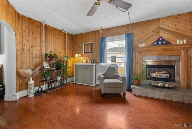 2654 Main St, Newfane, NY 14108 - living area with arched walkways, wooden walls, ceiling fan, wood finished floors, and a textured ceiling