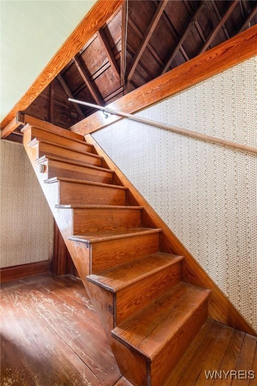 2654 Main St, Newfane, NY 14108 - stairs with wallpapered walls, hardwood / wood-style floors, vaulted ceiling, baseboards, and wood ceiling