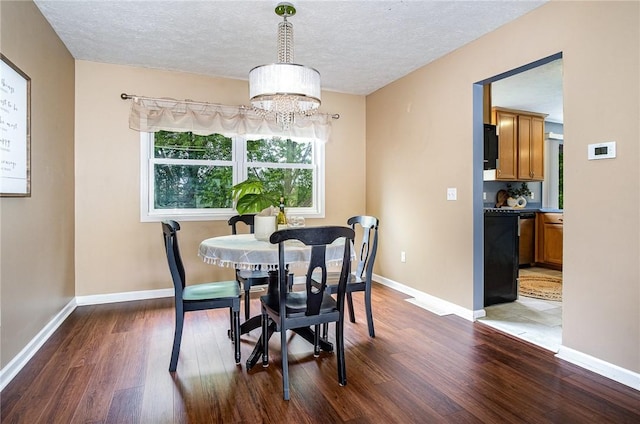 65 Geraldine Pkwy, Gates, NY 14624 - dining room with dark wood-style floors, a chandelier, a textured ceiling, and baseboards