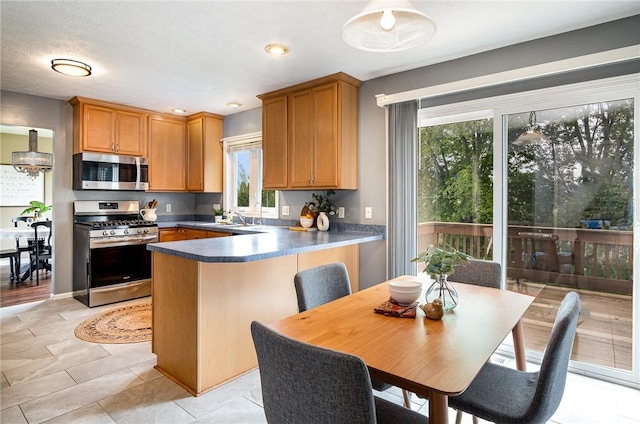 65 Geraldine Pkwy, Gates, NY 14624 - kitchen with stainless steel appliances, a peninsula, a sink, and dark countertops