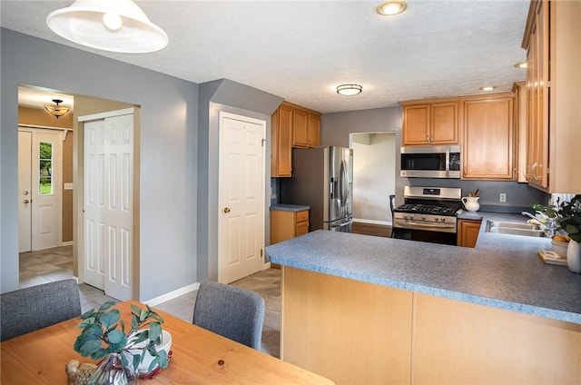 65 Geraldine Pkwy, Gates, NY 14624 - kitchen with stainless steel appliances, a peninsula, light tile patterned flooring, baseboards, and a sink