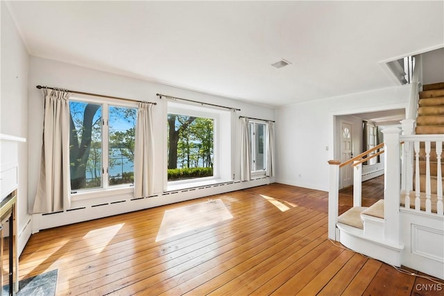 5199 W Lake Rd, Fleming, NY 13021 - unfurnished living room with baseboard heating, light wood-style floors, and stairs