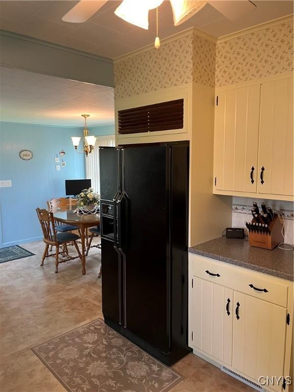 7 Roberts St, Adams, NY 13605 - kitchen with black fridge, dark countertops, light floors, white cabinetry, and ornamental molding
