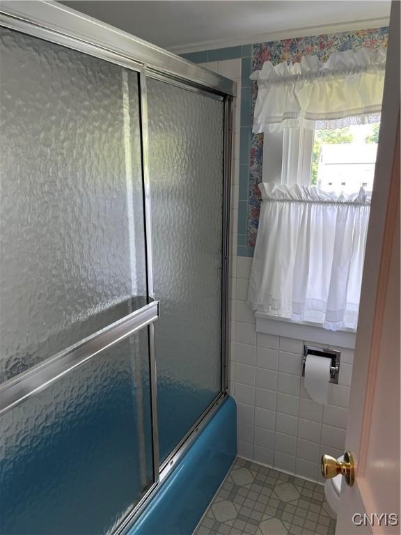 7 Roberts St, Adams, NY 13605 - bathroom with tile patterned flooring, shower / bath combination with glass door, and tile walls