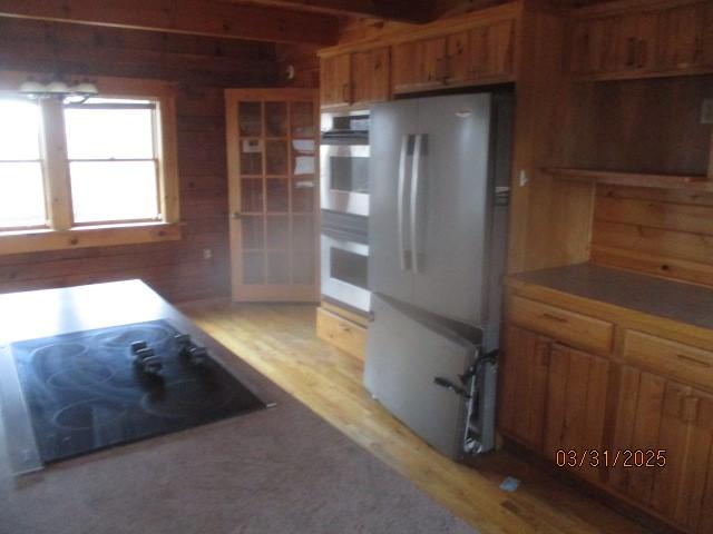 3709 Dean Rd, Hector, NY 14869 - kitchen with freestanding refrigerator, stainless steel double oven, black electric cooktop, brown cabinets, and light wood-type flooring
