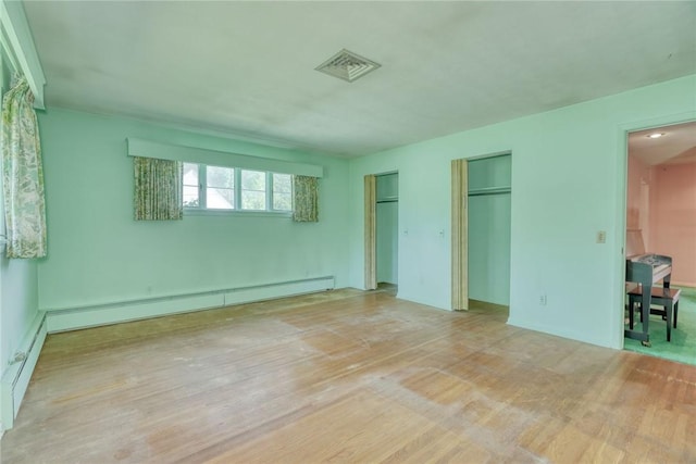 492 Drumm Rd, Webster, NY 14580 - unfurnished bedroom with two closets, wood finished floors, baseboard heating, and a baseboard heating unit