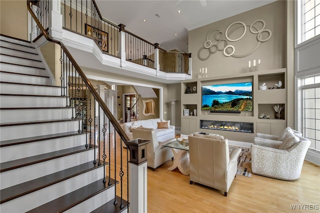 35 Pinegrove Ct, Elma, NY 14059 - living area with light wood finished floors, a towering ceiling, healthy amount of natural light, stairs, and a glass covered fireplace