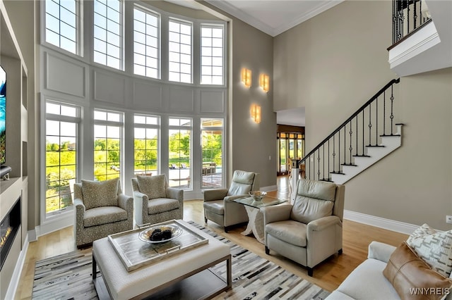 35 Pinegrove Ct, Elma, NY 14059 - living area featuring a towering ceiling, a glass covered fireplace, plenty of natural light, baseboards, and ornamental molding