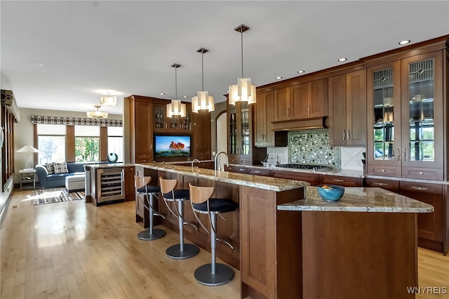 35 Pinegrove Ct, Elma, NY 14059 - kitchen with wine cooler, light wood-style floors, a center island with sink, light stone counters, and backsplash