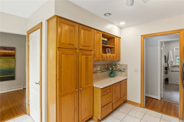 62 E Park Rd, Pittsford, NY 14534 - kitchen with decorative backsplash, baseboards, light tile patterned flooring, a baseboard radiator, and brown cabinets
