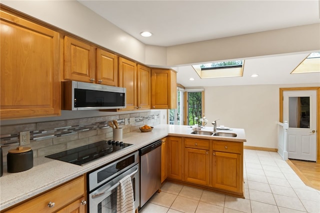62 E Park Rd, Pittsford, NY 14534 - kitchen with appliances with stainless steel finishes, a sink, backsplash, a skylight, and a peninsula