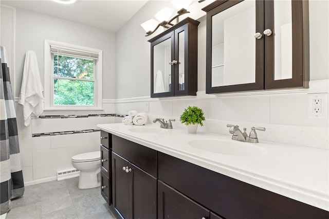 62 E Park Rd, Pittsford, NY 14534 - full bath with toilet, double vanity, a wainscoted wall, tile patterned floors, and tile walls
