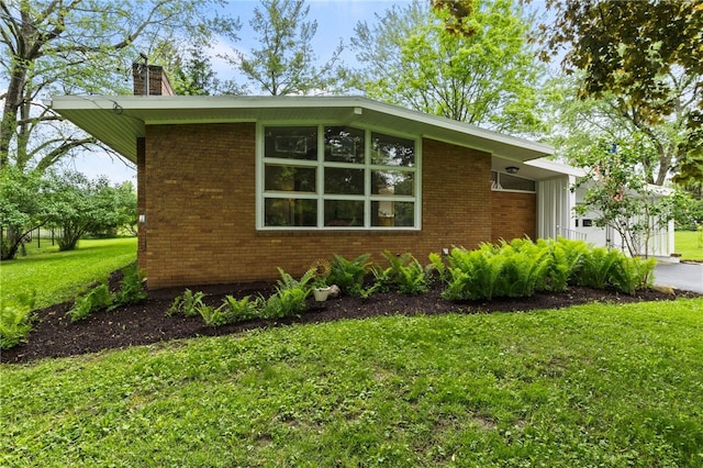62 E Park Rd, Pittsford, NY 14534 - view of side of home featuring a yard, a chimney, and brick siding