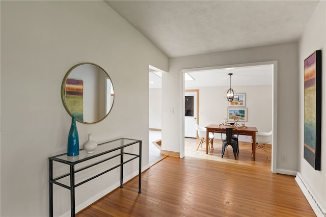 62 E Park Rd, Pittsford, NY 14534 - hallway with wood finished floors, baseboard heating, a chandelier, and baseboards