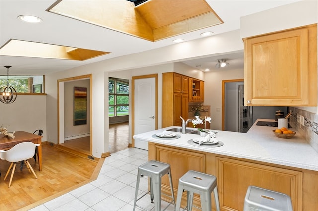 62 E Park Rd, Pittsford, NY 14534 - kitchen featuring a peninsula, a sink, a baseboard heating unit, a skylight, and light tile patterned floors