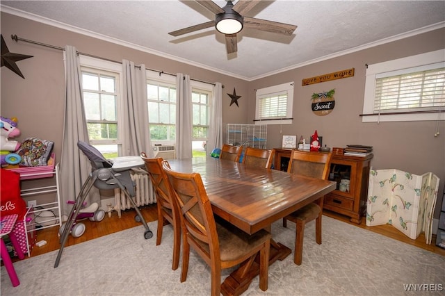 5557 Seneca St, West Seneca, NY 14224 - dining area featuring light wood-style floors, ornamental molding, ceiling fan, and radiator heating unit