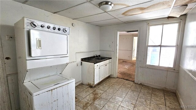 198 Mulberry St, Buffalo, NY 14204 - kitchen featuring stacked washing machine and dryer, a sink, a drop ceiling, healthy amount of natural light, and a wainscoted wall