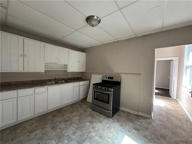325 Rhode Island St, Buffalo, NY 14213 - kitchen featuring stainless steel gas range, a drop ceiling, a sink, dark countertops, and white cabinetry