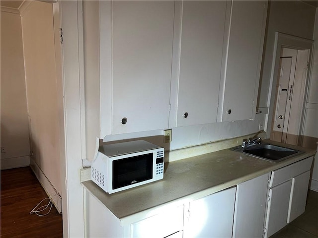 571 Lake Ave, Rochester, NY 14613 - kitchen with white microwave, a sink, dark wood-style flooring, white cabinetry, and light countertops